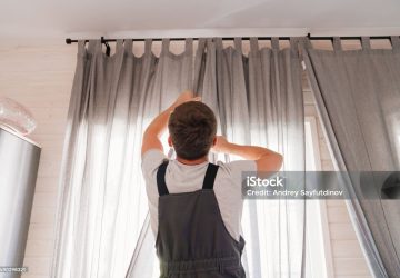 bricoleur entrain de monter de poser un rideau sur une tringle