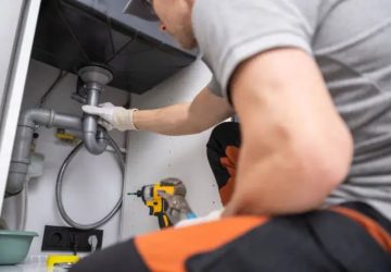 bricoleur entrain de remettre en place une canalisation sous le lavabos