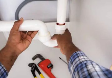bricoleur qui débouche un siphon blanc